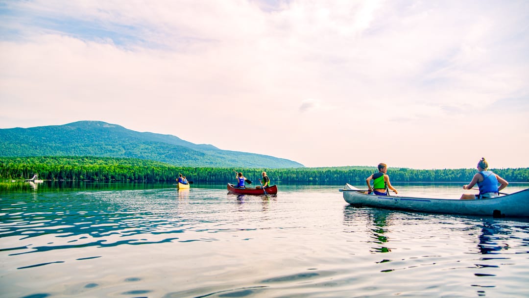 campers canoeing in the lake at sunset