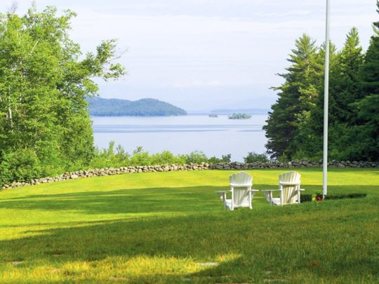 Front lawn of brookwoods with two chairs and the lake