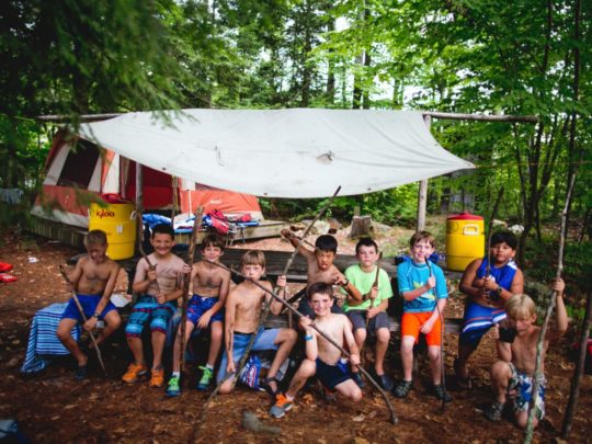 Group of muddy boys holding sticks at the Brookwoods Explorer program
