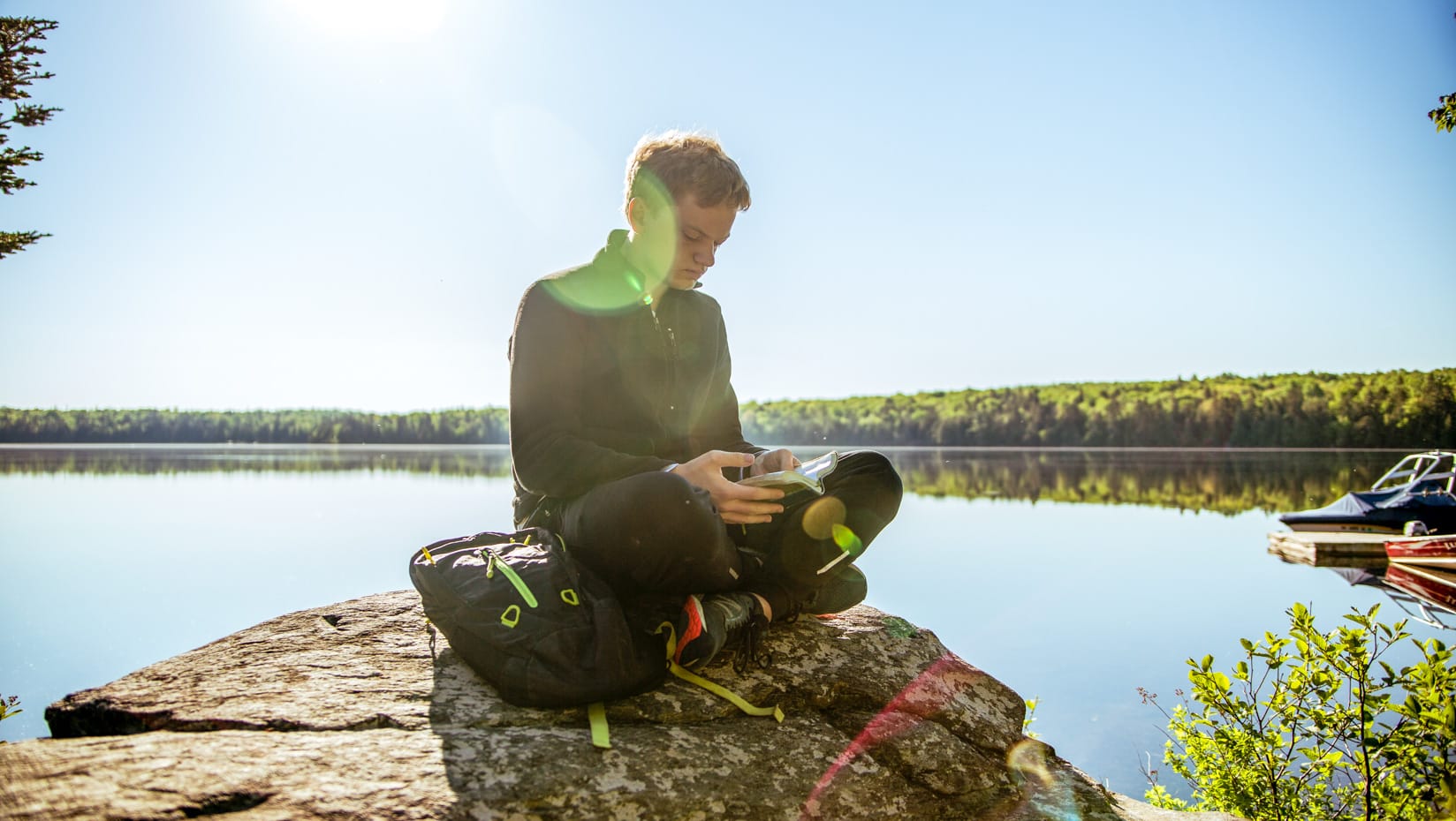 camper reading the bible by the lake