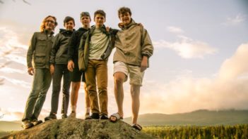 Five boys standing on a rock by the lake