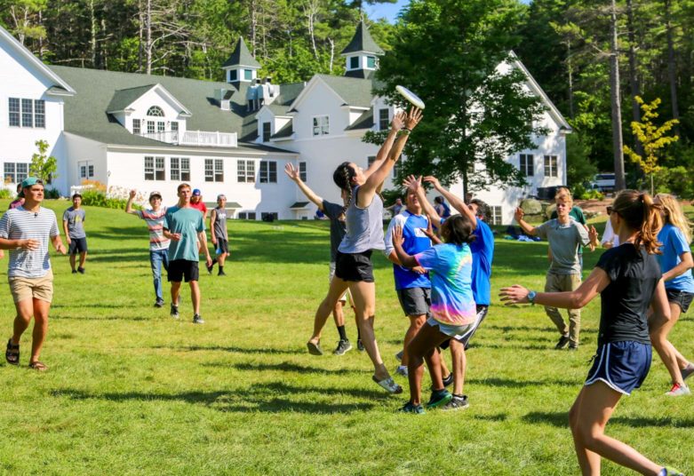 Campers playing frisbee on the front lawn