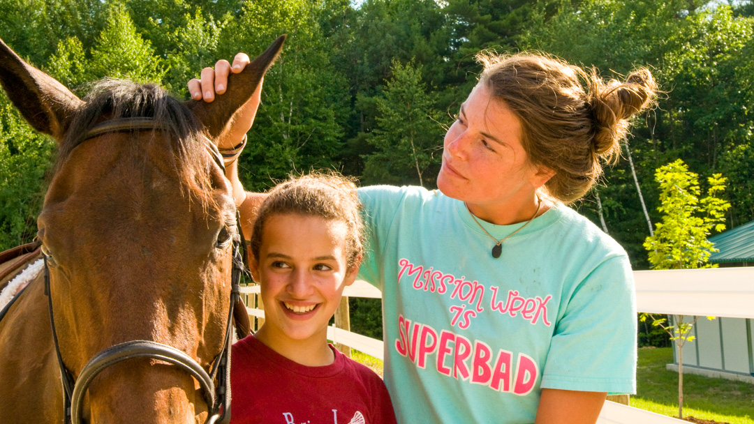 Camper and staff petting a horse