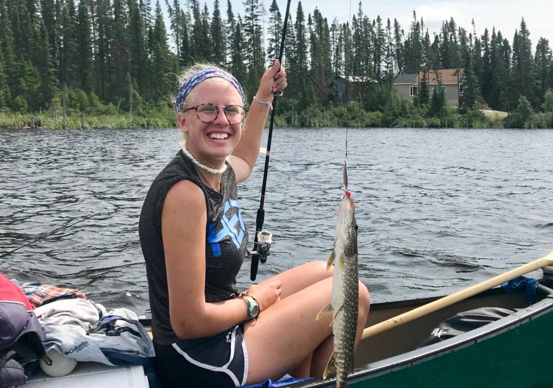 Girl catching a fish while canoeing on the Leadership Development Program