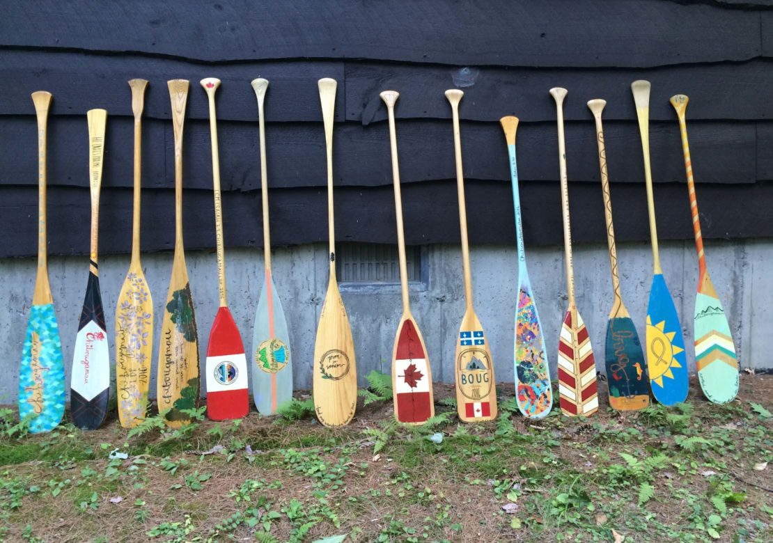 Decorated paddles leaning on a cabin on the Leadership Development Program