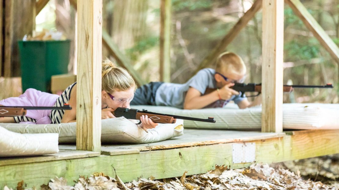 Campers laying down and shooting rifles