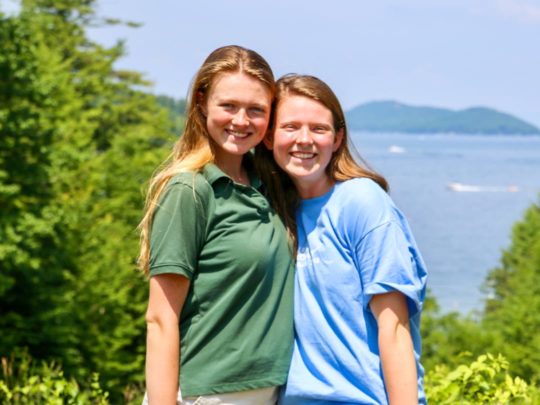 Two staff standing by the lake