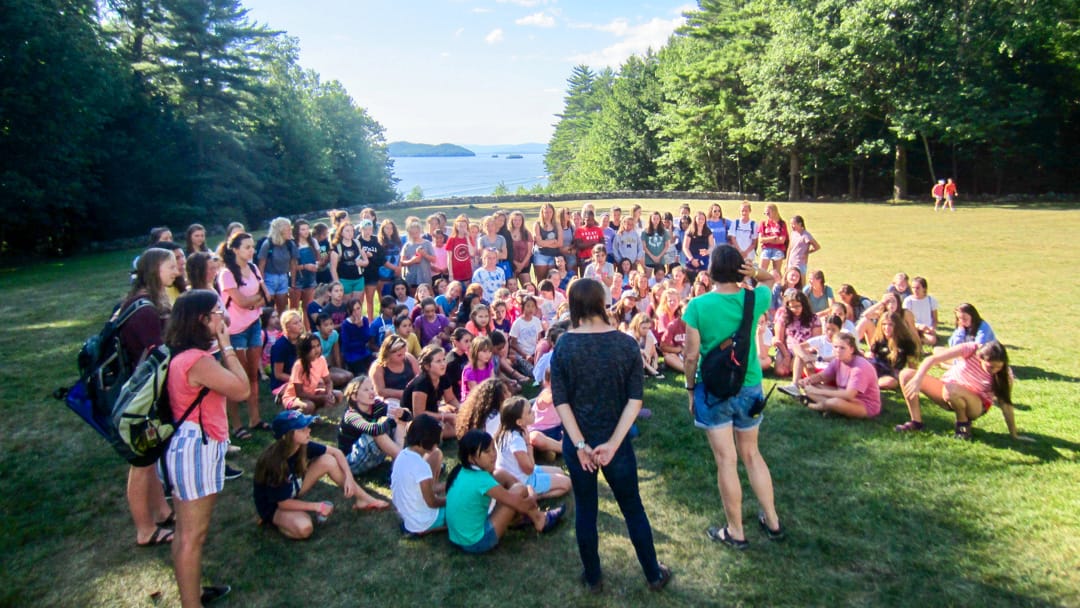 Staff speaking to group of campers on the front lawn