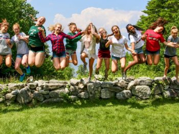Group of staff and campers jumping off rock wall