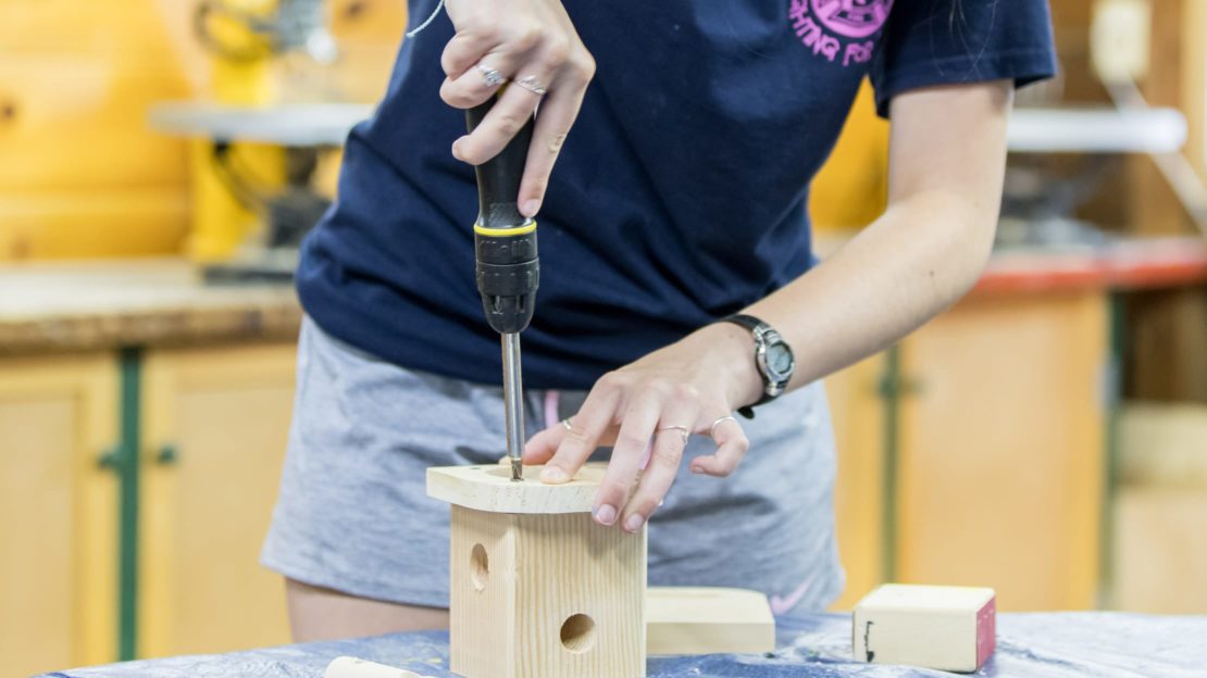 Girl building a wooden bird box