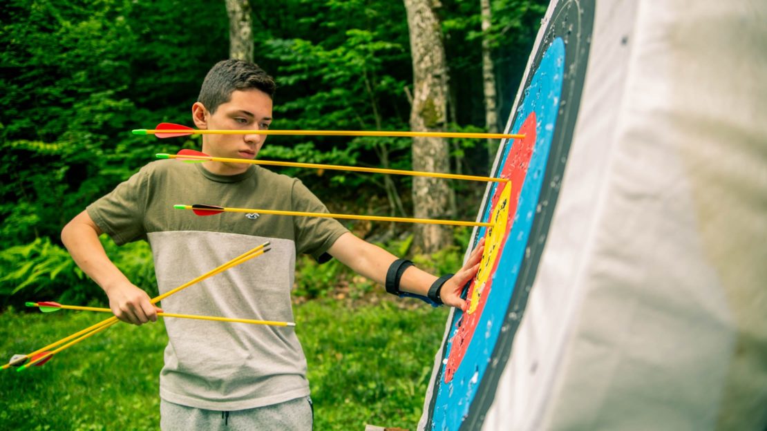 camper pulling out archery arrows from target