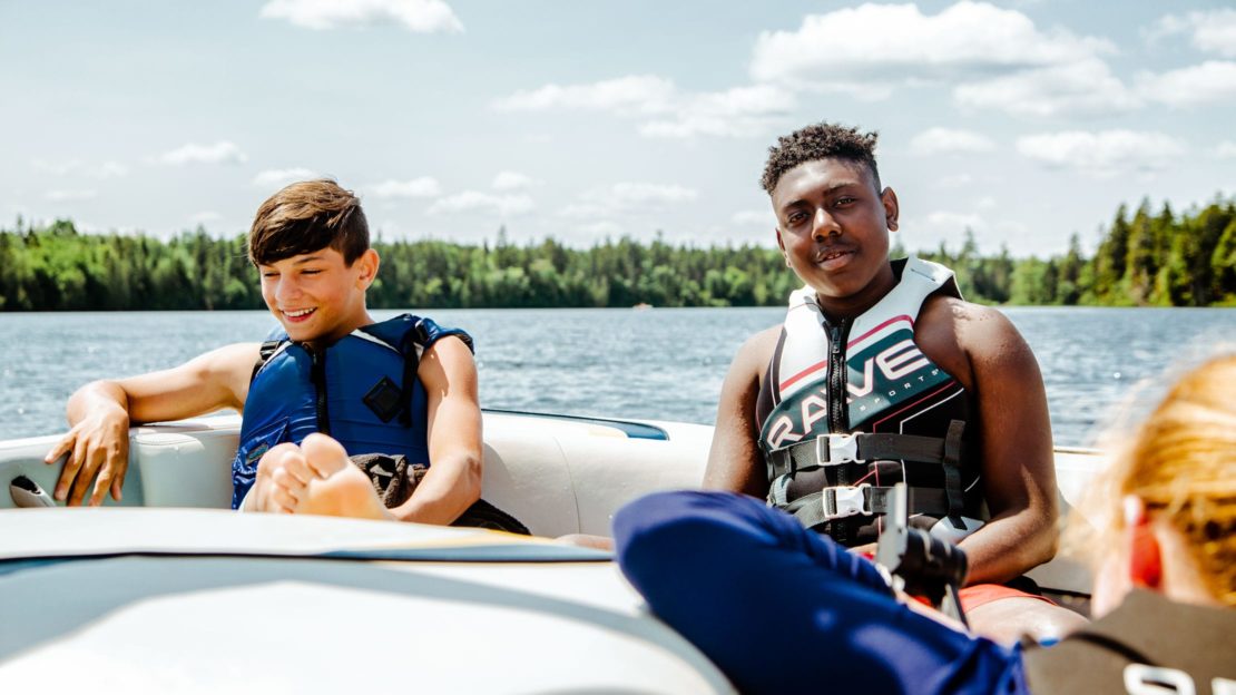 Camper and staff sitting in motorboat