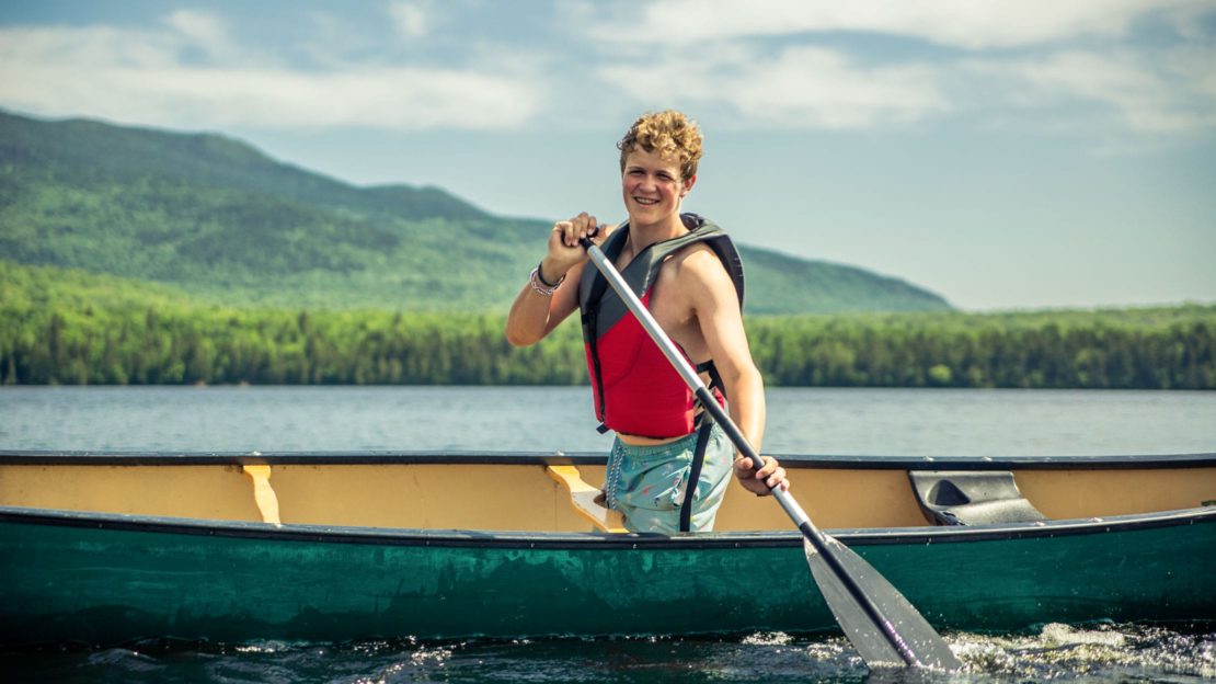 Male camper canoeing on lake