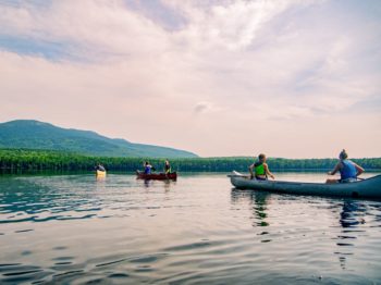 Campers canoeing on the lake at Moose River Outpost with mountains in the background