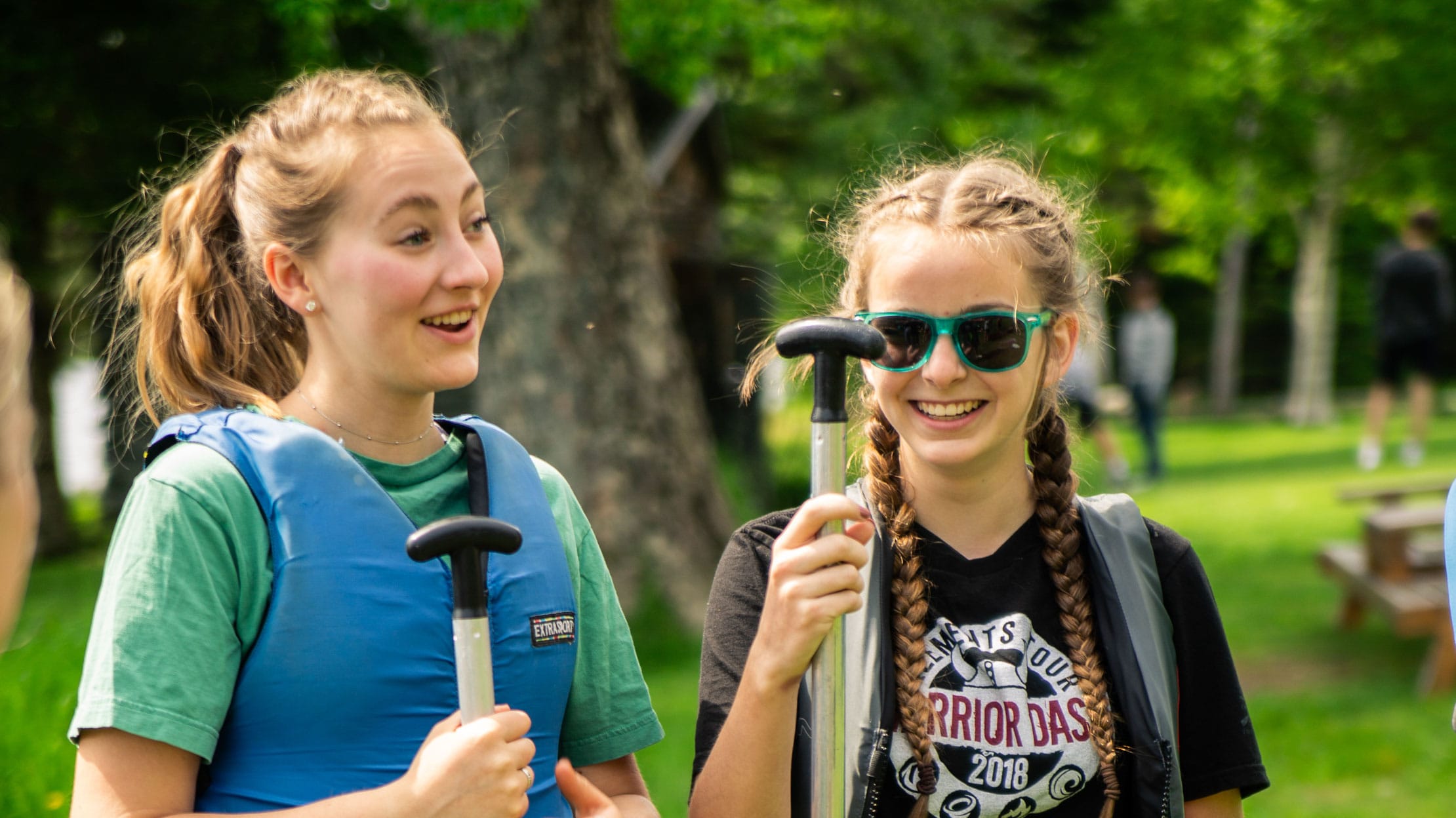 Two girls talking while holding paddles