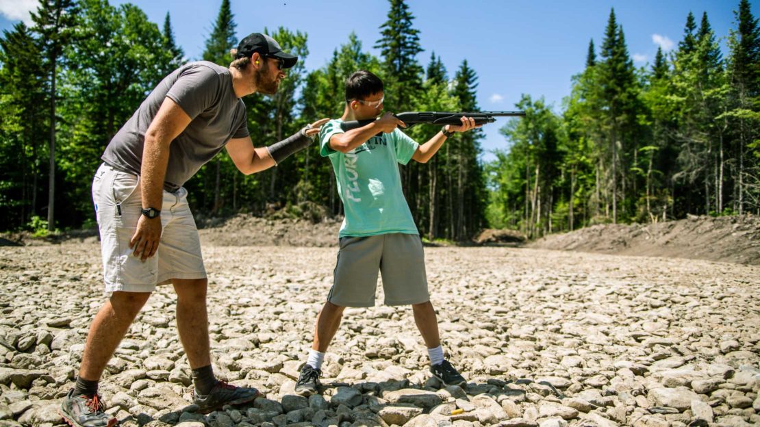 Staff helping boy aim rifle