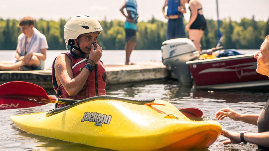 Camper learning to roll a kayak in the lake