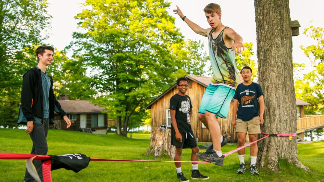 Campers slack-lining while staff watches 