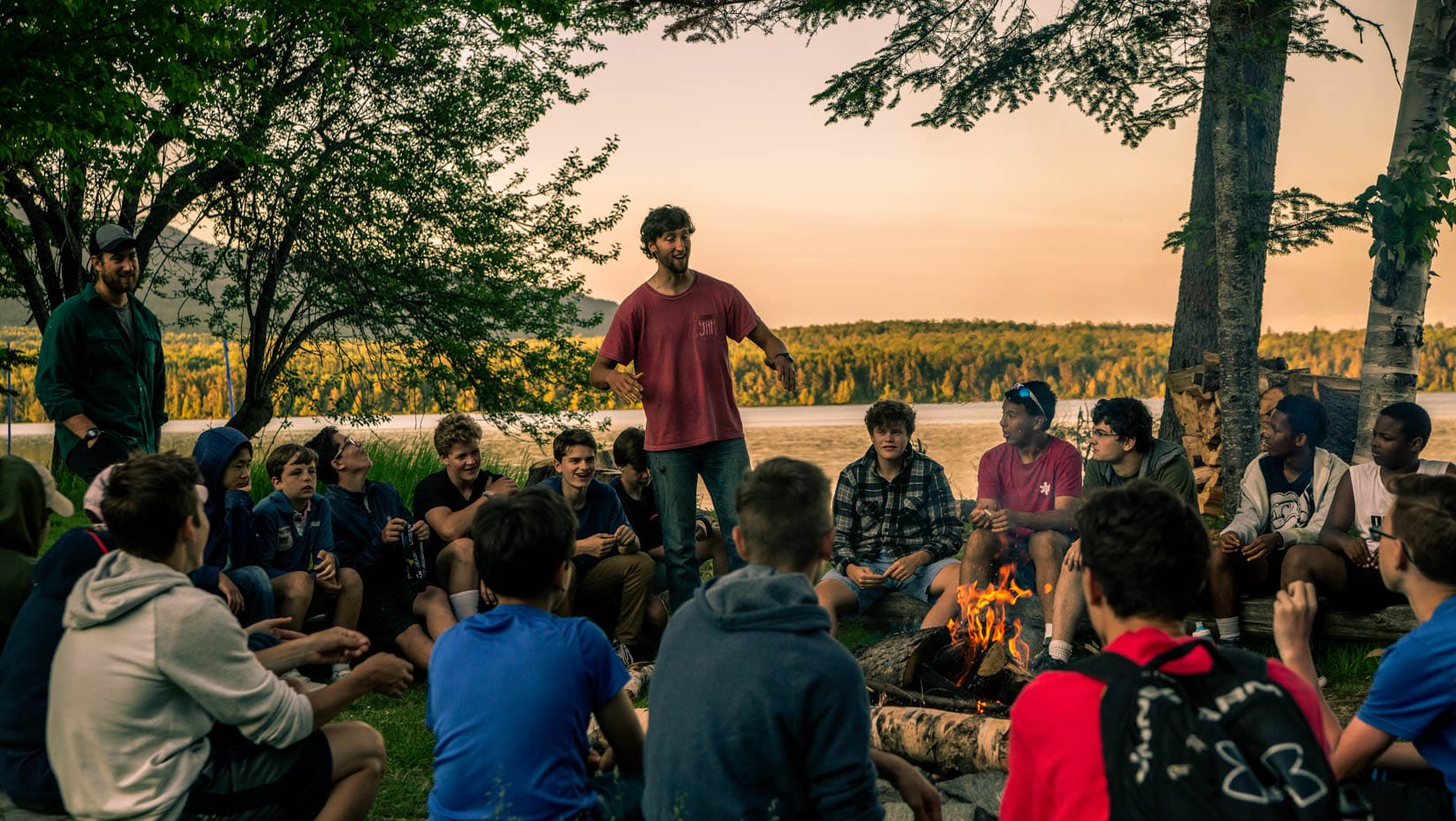 Staff leading a campfire circle at sunset