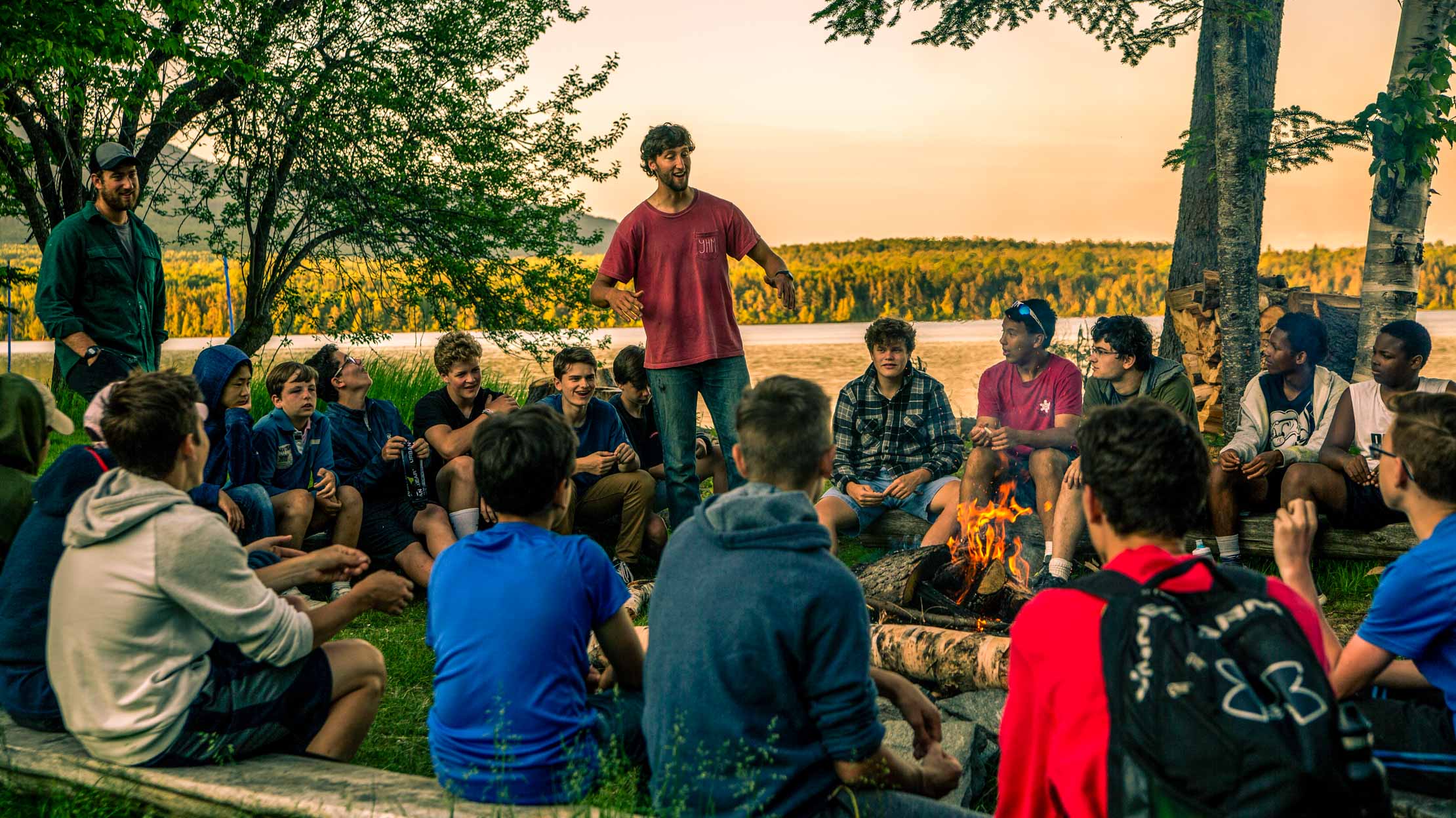 Staff at a campfire with campers sitting