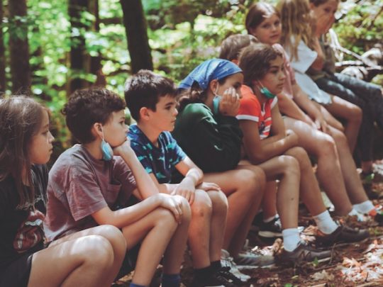 a group of campers sitting on a log