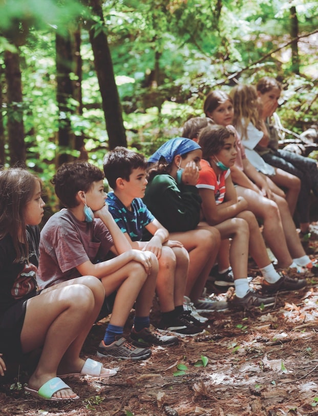 a group of campers sitting on a log